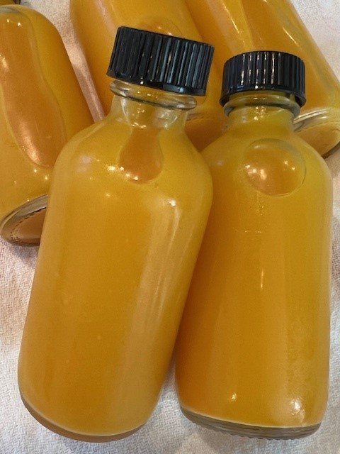 Picture of lemon ginger turmeric wellness shots in small glass bottles.