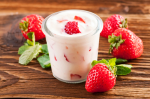 Picture of strawberry kefir on a table with whole strawberries next to the jar.